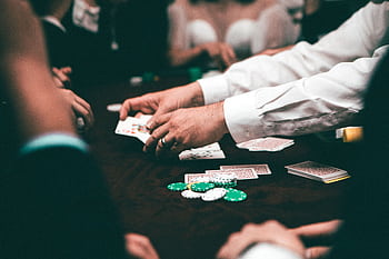 An intense poker game featuring players and poker chips on the table in an indoor setting. HD wallpaper