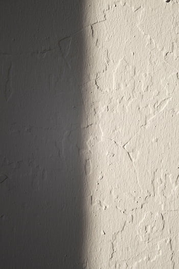Close-up of a textured plaster wall with light and shadow creating contrast. HD phone wallpaper