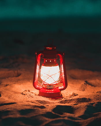 A glowing red lantern lights up the sandy beach during nighttime, creating a warm, cozy atmosphere. HD phone wallpaper