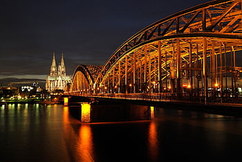Captivating night shot of Cologne Cathedral and Hohenzollern Bridge reflected on the Rhine River. HD wallpaper