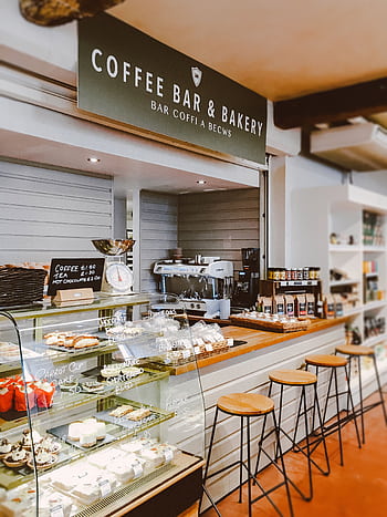 Inviting indoor scene of a bakery cafe with pastries and seating. HD phone wallpaper