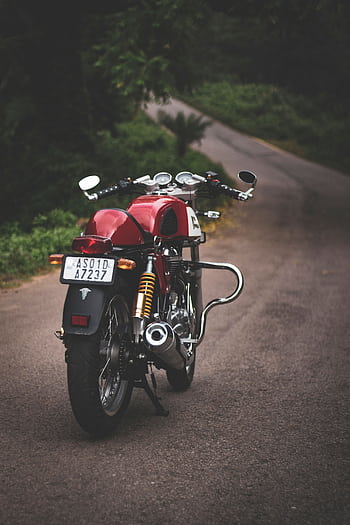 Rear view of a classic red motorcycle parked on a quiet country road, showcasing vintage style. HD phone wallpaper