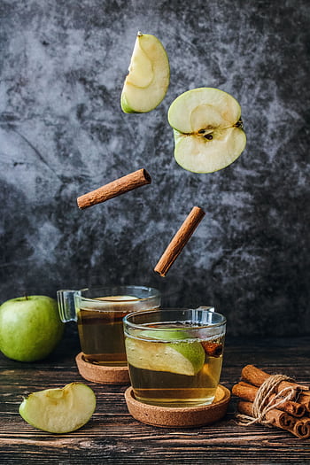Aromatic apple tea with cinnamon sticks and fresh apple slices on a rustic table. HD phone wallpaper