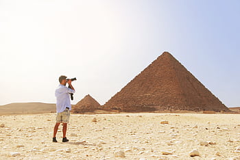 grapher taking a of the Pyramid of Giza under the bright Egyptian sun. HD wallpaper