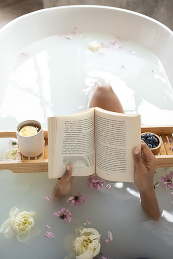 Peaceful bath scene with a book and flowers, creating a serene and tranquil atmosphere. HD phone wallpaper