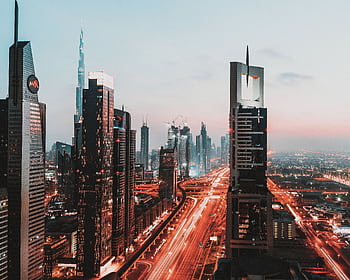 Dynamic view of Dubai's illuminated skyline featuring iconic skyscrapers at sunset. HD wallpaper
