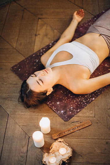 Woman practicing relaxation yoga with candles set for a calming atmosphere. HD phone wallpaper