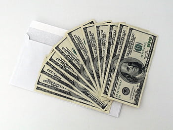 Fan of US $100 bills partially out of a white envelope on a white background. HD wallpaper