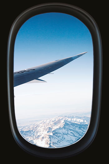 Stunning view of snow-capped mountains seen from an airplane window, showcasing the beauty of air travel. HD phone wallpaper