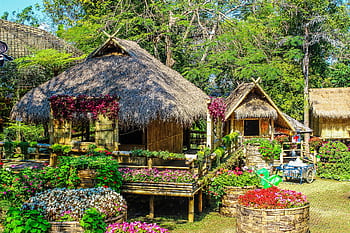 Rustic huts nestled in a lush garden with colorful flowers creating a serene atmosphere. HD wallpaper