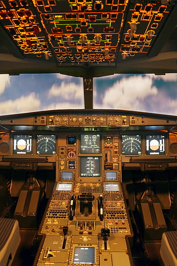 Interior view of an advanced airplane cockpit with illuminated control panels and displays. HD phone wallpaper