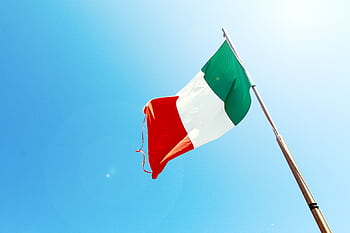 Vivid of the Italian flag waving on a flagpole against a bright blue sky. HD wallpaper
