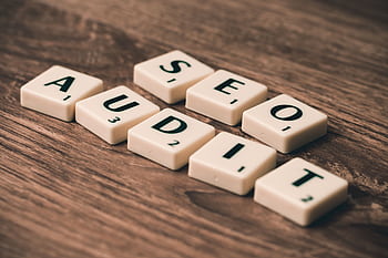 Scrabble tiles spelling SEO Audit on wooden surface, symbolizing digital marketing strategies. HD wallpaper
