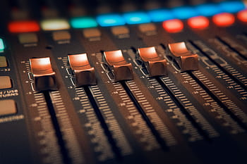 Detailed close-up of an audio mixer with illuminated controls in a studio setting. HD wallpaper