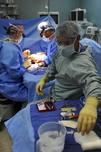 Team of surgeons in a hospital operating room conducting a surgery. HD phone wallpaper