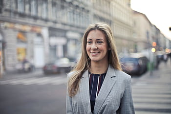 Confident businesswoman smiling outdoors in urban Budapest setting. HD wallpaper