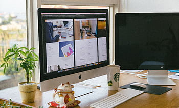 A bright workspace featuring an iMac, plant, and decor in a daylight setting. HD wallpaper