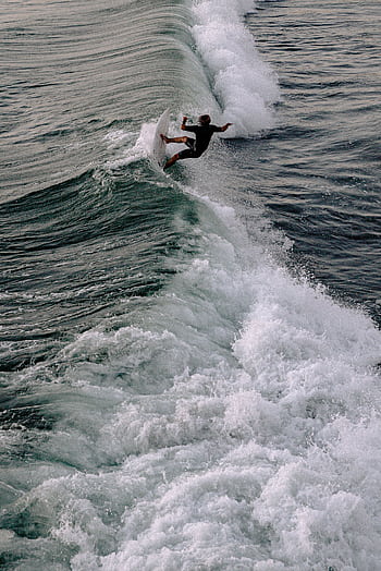 Captivating of a surfer riding a powerful wave, showcasing skill and thrill in ocean sports. HD phone wallpaper