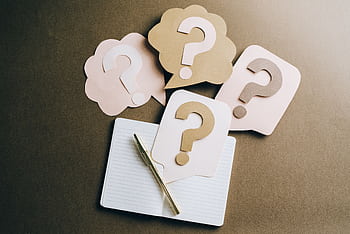 Flat lay of question mark paper crafts on a notebook, symbolizing questions and ideas. HD wallpaper