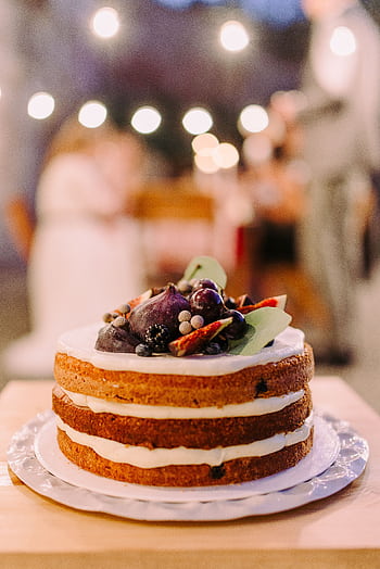 Naked-style cake topped with berries in an outdoor nighttime setting, perfect for elegant celebrations. HD phone wallpaper