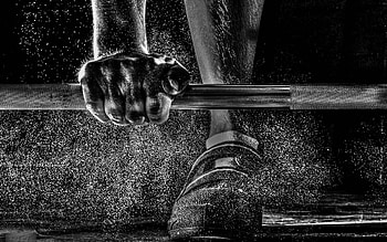 A Man Training Weight Lifting Barbell With Dust Flying Over His Shoes Black And White HD wallpaper