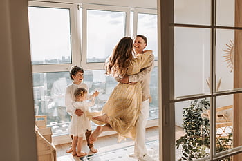 A joyful family embraces in a sunlit modern apartment, celebrating togetherness and love. HD wallpaper