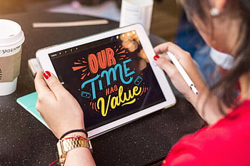 Woman using a tablet to create colorful digital art emphasizing time value. HD wallpaper