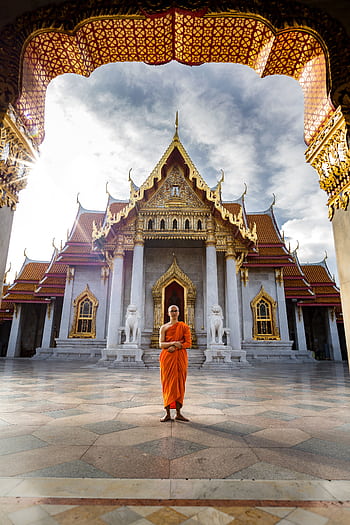 A Buddhist monk standing in front of the iconic Wat Benchamabophit Temple, Bangkok, capturing spiritual tranquility. HD phone wallpaper
