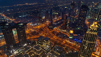 A dazzling aerial view of Dubai's illuminated skyline featuring highways and skyscrapers at night. HD wallpaper