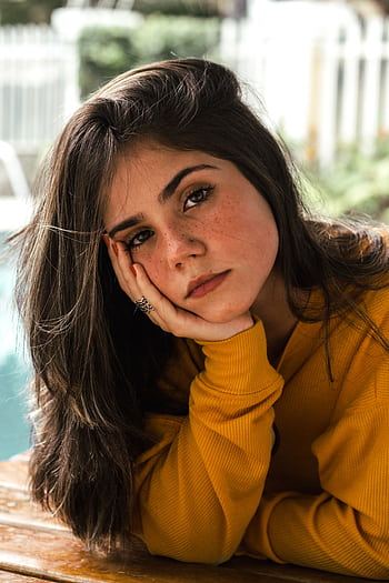 A young woman in a yellow sweater poses thoughtfully by a poolside. HD phone wallpaper
