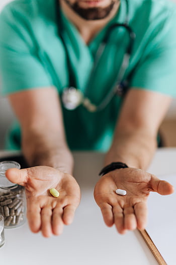 A doctor offers two different pills, symbolizing medical choices in healthcare. HD phone wallpaper