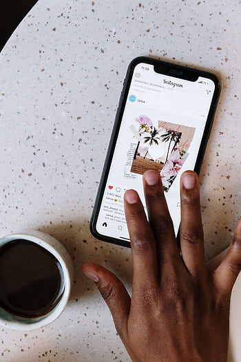 Close-up of hand scrolling Instagram on smart near coffee cup on table. HD phone wallpaper