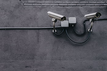 Two surveillance cameras mounted on a concrete wall, highlighting security technology. HD wallpaper