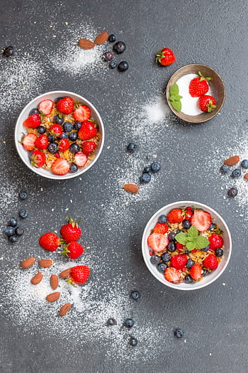 Top view of bowls filled with cereal, strawberries, and blueberries, perfect for a healthy breakfast. HD phone wallpaper