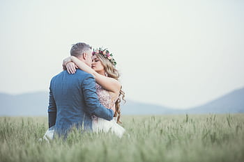 A couple embracing romantically in a lush summer field, showcasing love's beauty. HD wallpaper