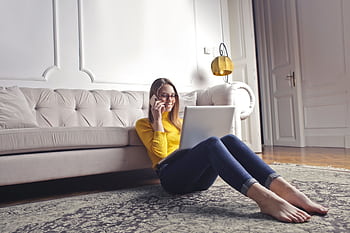 Woman in yellow sweater using laptop and , relaxing at home on carpet. HD wallpaper