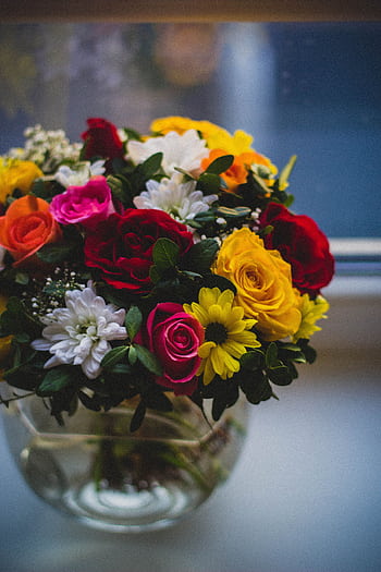 A colorful bouquet of roses and daisies in a glass vase on a windowsill, capturing the essence of spring. HD phone wallpaper