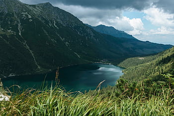 Majestic view of a serene lake surrounded by Tatra Mountains under a cloudy sky in Poland. HD wallpaper
