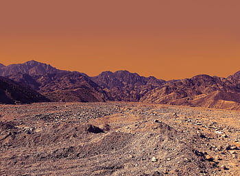 Stunning landscape of South Sinai's rocky desert under a vibrant orange sky. HD wallpaper
