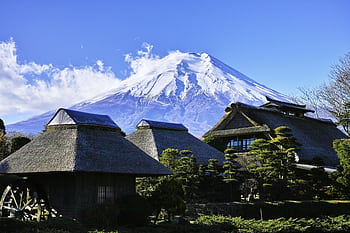 Scenic view of traditional thatched roof houses with Mount Fuji in the background on a clear day. HD wallpaper