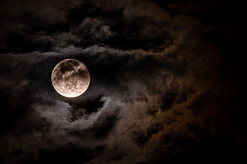 Captivating full moon obscured by dark clouds in a night sky, creating a mysterious ambiance. HD wallpaper