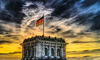 Vibrant sunset over a historic Berlin monument with the German flag waving. HD wallpaper