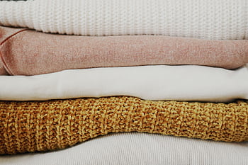 A close-up view of neatly stacked, warm fabrics showcasing various textures and colors. HD wallpaper