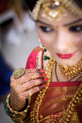 Close-up of an Indian bride adorned with traditional jewelry and henna decorations. HD phone wallpaper