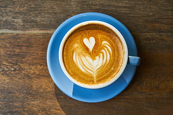 Top view of a latte with heart art in a blue cup on a wooden table. HD wallpaper