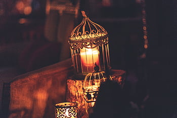A glowing candle inside an ornate lantern creates a warm ambiance perfect for festive occasions like Ramadan. HD wallpaper