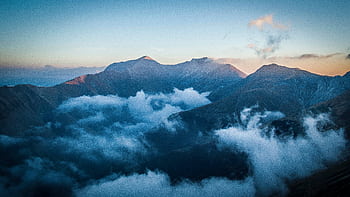 Serene mountain landscape with clouds enveloping peaks at dawn, captured in Montemonaco, Italy. HD wallpaper