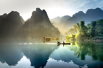 Peaceful scene of a boat on a river amidst stunning mountains in Tuyên Quang, Vietnam. HD wallpaper