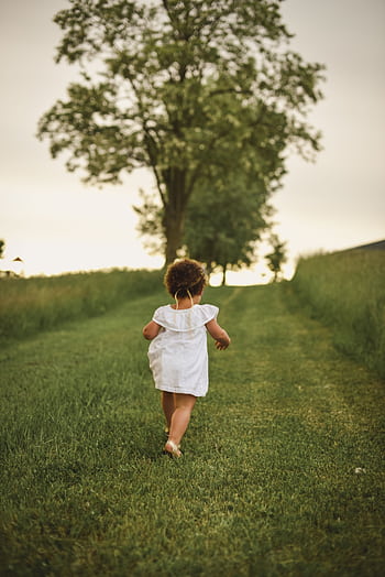 A young child runs ly down a grassy path surrounded by lush trees in a park during summer. HD phone wallpaper