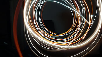 Dynamic long exposure shot of swirling light streaks creating an abstract pattern on a dark background. HD wallpaper